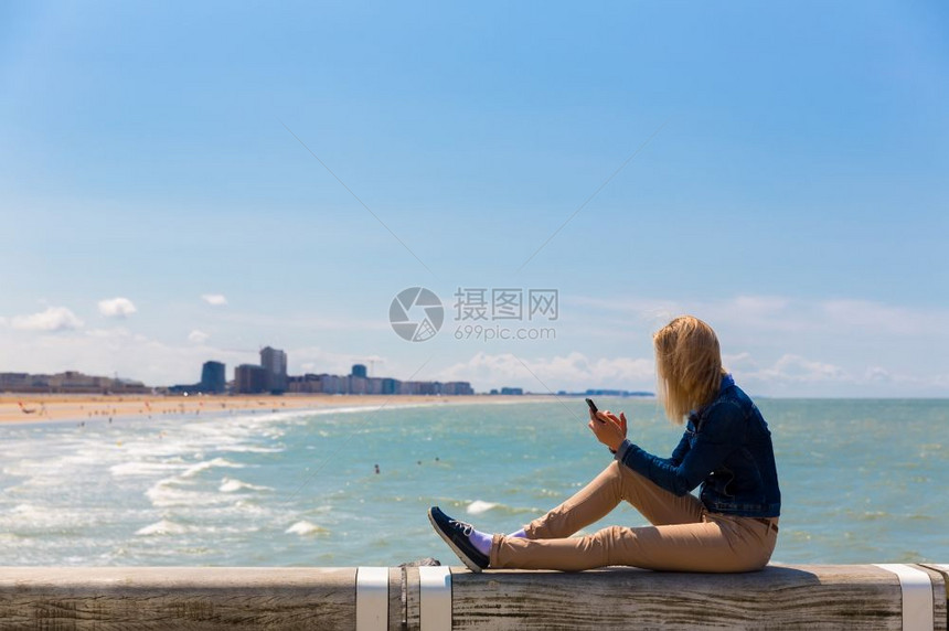 夏季在欧洲著名的海滩岸拿着手机的女游客图片