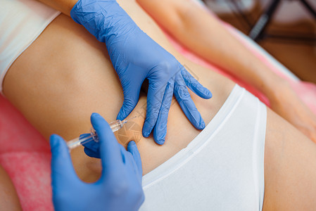 女人注射针剂戴手套的美容师为女病人腹部注射针剂背景