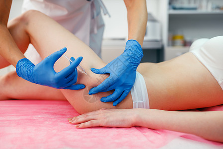 女人注射针剂美容师戴手套在顾客大腿上注射针剂背景