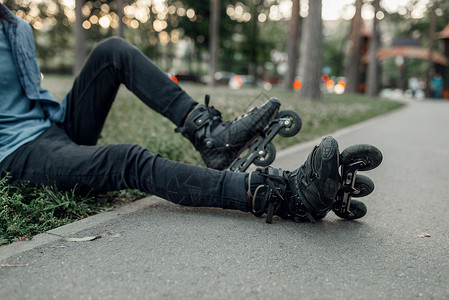 年轻男子穿着轮滑鞋坐在草地上休息图片