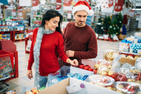 在超市购买圣诞树玩具的夫妇背景图片