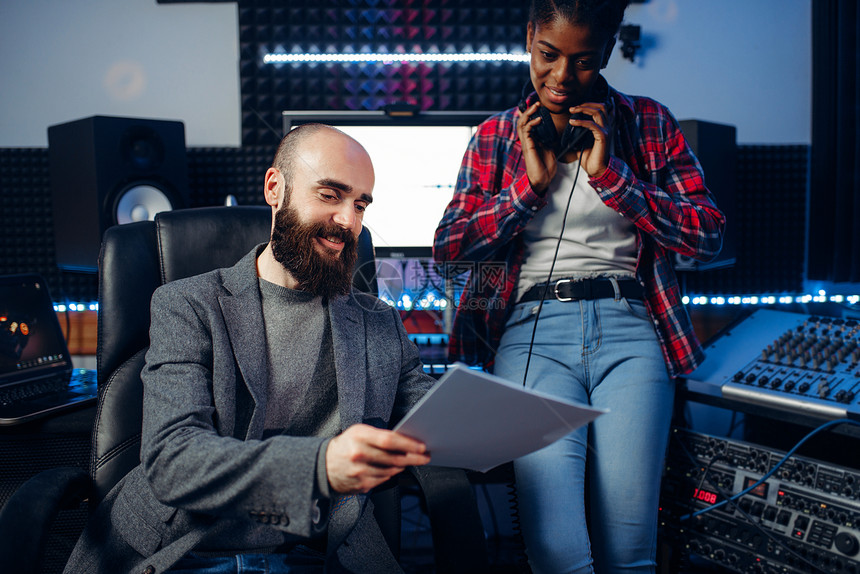男录音制员和耳语女歌手在录音室聆听作品专业频和乐混合技术图片