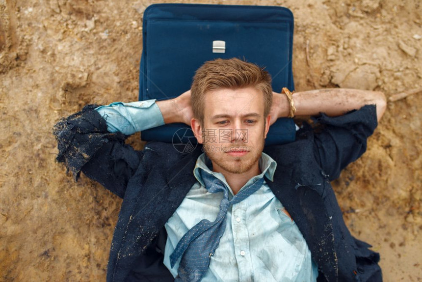 破产的男商人枕着公文包躺在海滩上图片