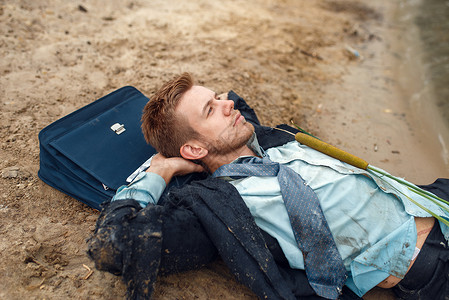 破产的男商人枕着公文包躺在海滩上图片