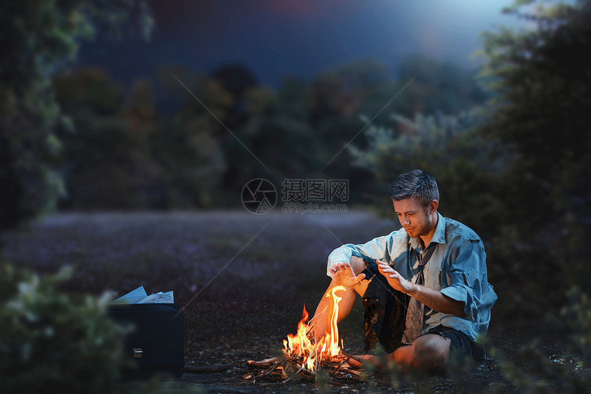 破产的男商人夜晚时坐在火堆旁取暖图片
