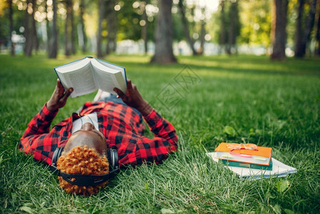 黑人青年躺在草地上看书学习图片