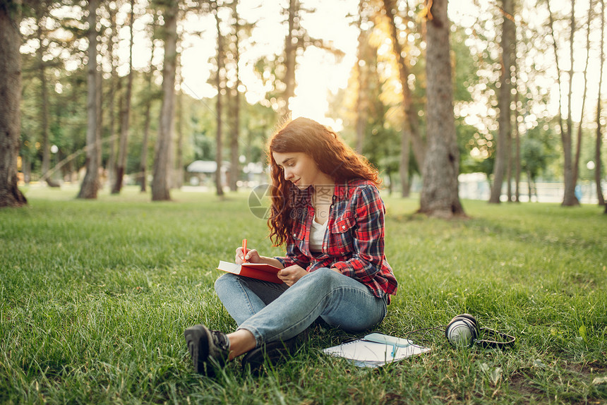 女学生在公园的草地上写字图片