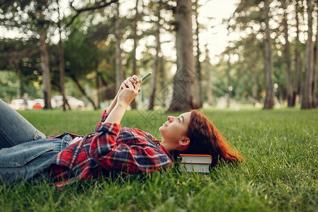 女学生躺在公园的草地上看手机图片