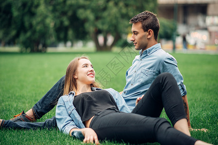 年轻男女躺在公园草地上聊天图片