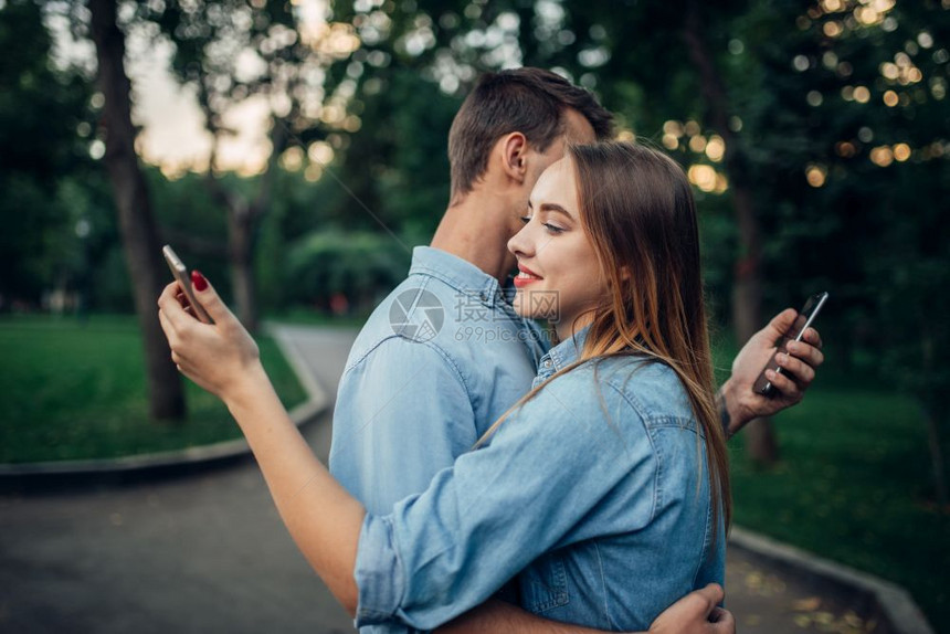 公园里拥抱的男女使用手机社交图片