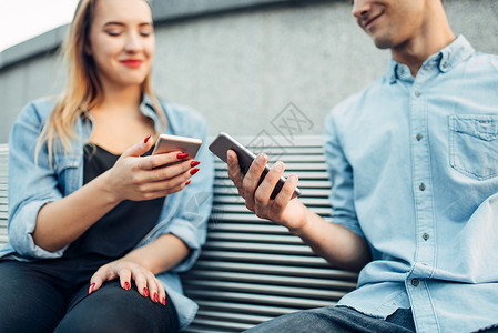 手机成夫妇坐在长椅上看智能手机社交者图片