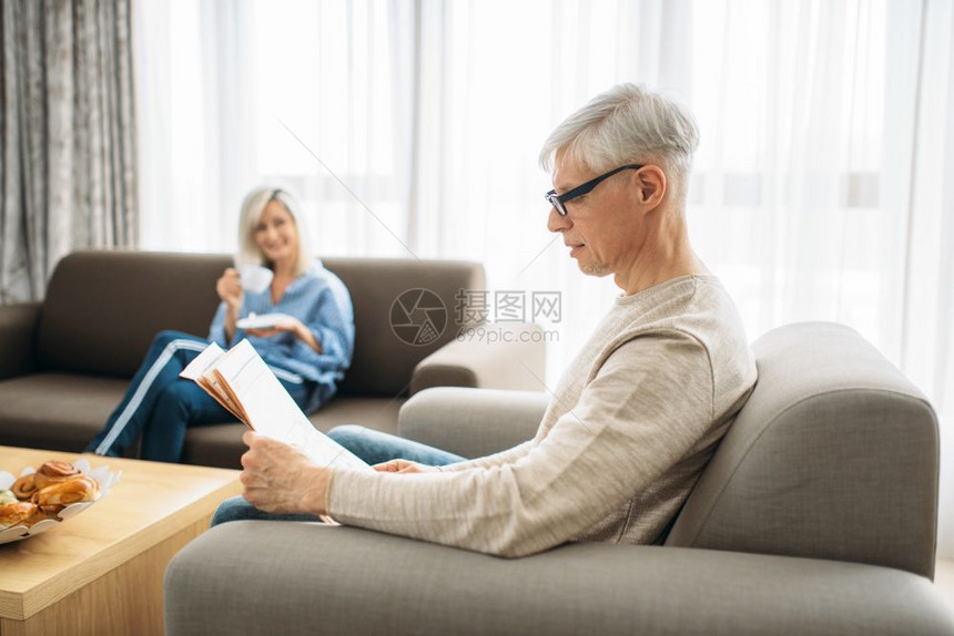 年长的夫妇在沙发上看报纸喝咖啡图片