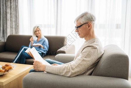 年长的夫妇在沙发上看报纸喝咖啡图片