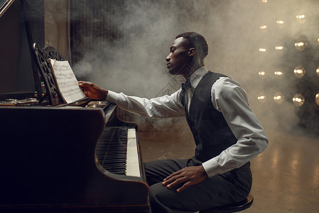黑人音乐家在钢琴前看琴谱背景图片