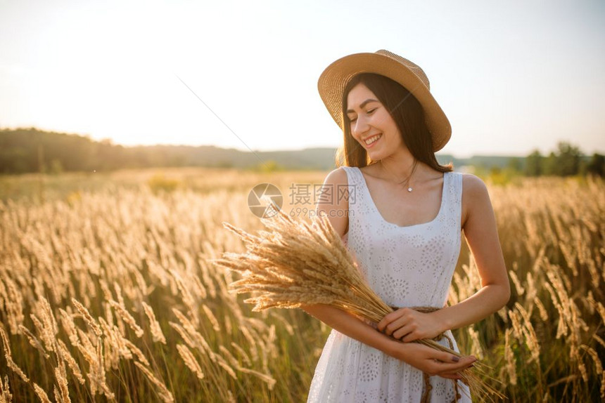 麦田中年轻女子双手捧着一束小麦图片