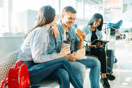 推迟离境的旅客坐在机场等候厅吃东西图片