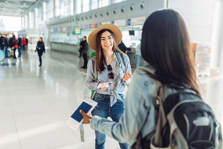 2名手持户照的女游客在机场聊天图片