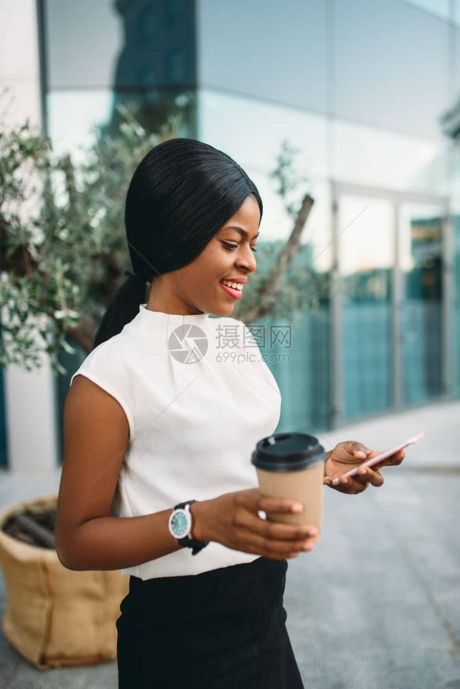 年轻的职场女性拿着咖啡玩手机图片