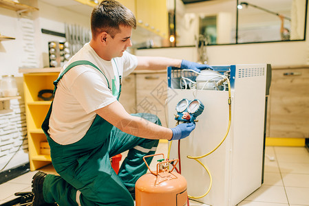 穿制服的工人在家中填充冰箱的压缩机修理冰箱职业专服务图片