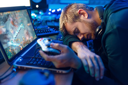 男玩家游戏后睡在笔记本电脑上图片