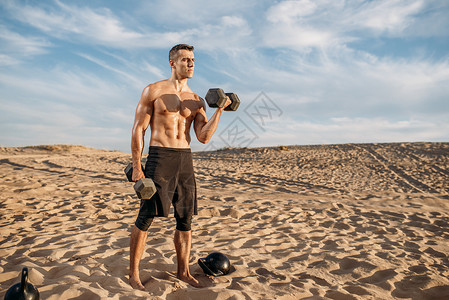 在沙漠上举着壶铃的肌肉男图片