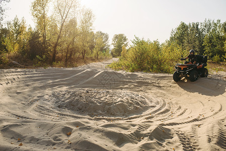 戴头盔的骑手骑着山地摩托车穿越沙漠丘图片