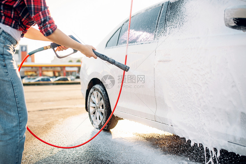 夏天年轻妇女用自助高压水在户外清洗车辆上的泡沫图片