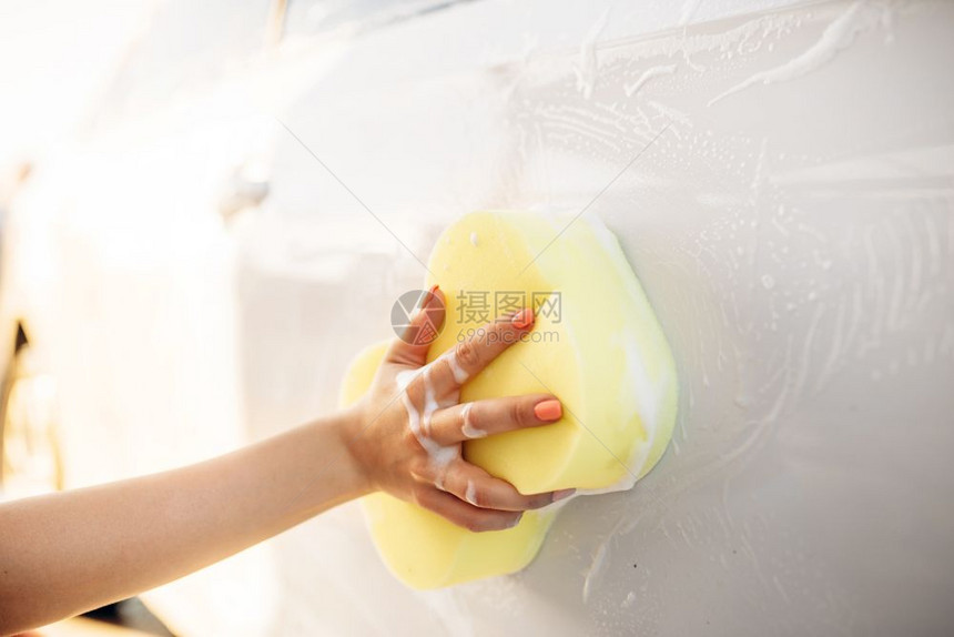 夏天年轻妇女在户外用海绵清洗车辆上的泡沫图片