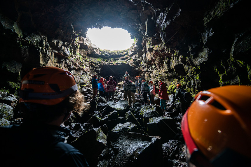 一群游客探索冰原的劳法希尔火山洞穴图片