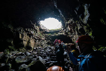 一群游客探索冰原的劳法希尔火山洞穴图片