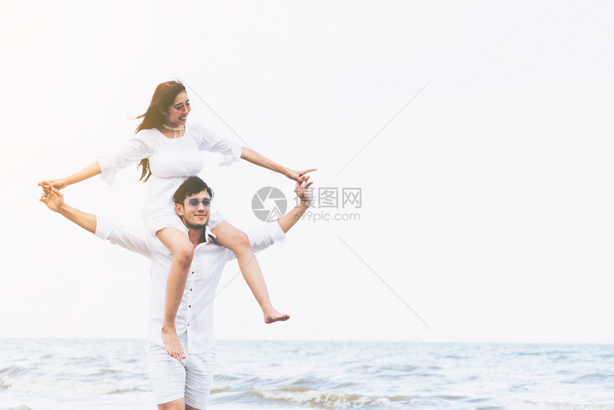 女子坐在男友肩膀上在沙滩玩耍图片