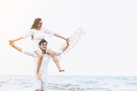 女子坐在男友肩膀上在沙滩玩耍图片