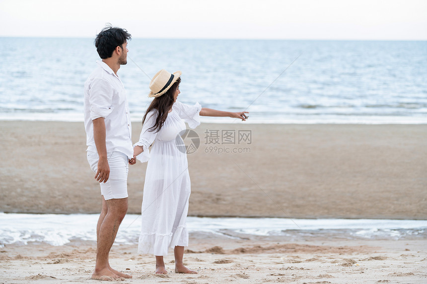 一对年轻夫妇在海边沙滩上看海图片