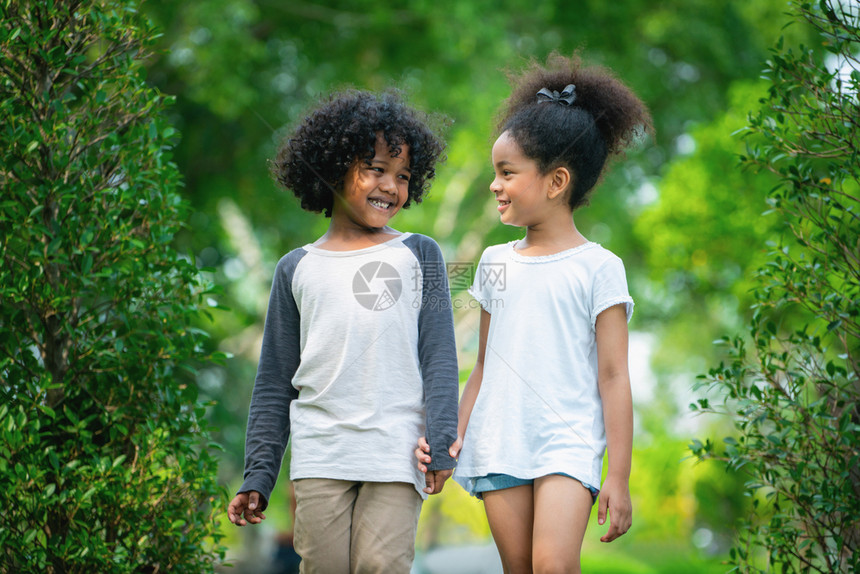 公园里快乐的小男孩小女孩两个一起在花园里散步图片