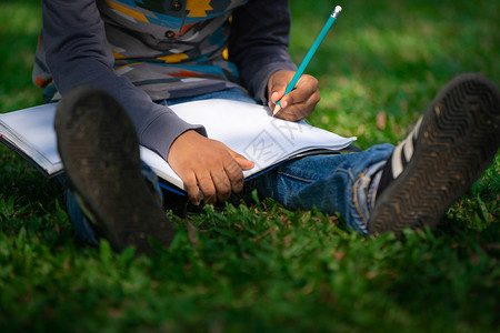 小男孩坐在草地上写字图片