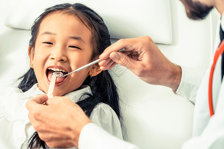 友好的年轻牙医在科诊所检查儿童牙齿图片