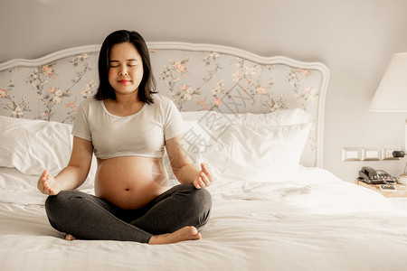 孕妇在家里卧室的床上做瑜伽图片