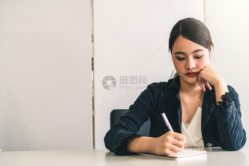 美丽的年轻女士坐在办公桌旁写信件图片