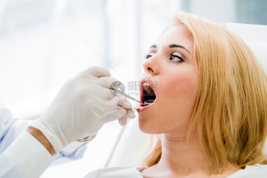 牙医在给女病人检查牙齿图片
