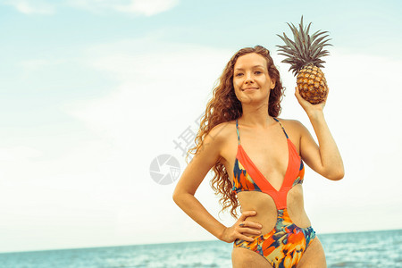 穿着泳衣的美女在海滩上拿着菠萝图片