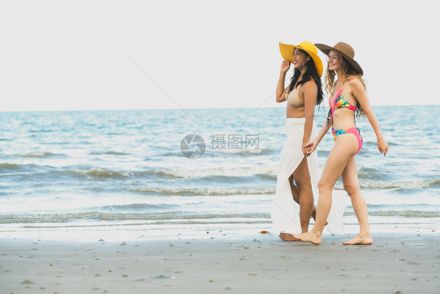 穿着比基尼的女子在沙滩散步图片