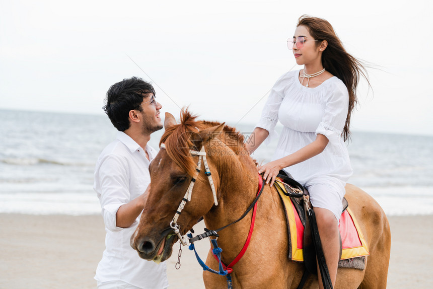 夫妇在热带海滩骑马图片
