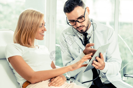 男医生和女病人看平板电脑以获取保健数据记录和医疗服务图片