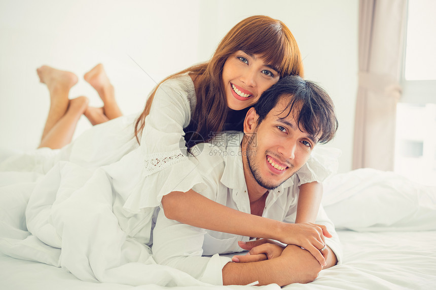 快乐的年轻夫妇早晨醒来后在家中卧室放松图片