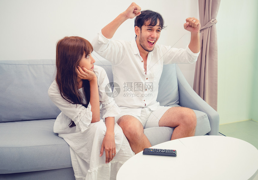 快乐的年轻夫妇在沙发上看电视图片