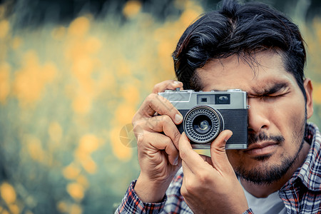 年轻时装男用古老的摄影机拍照图片