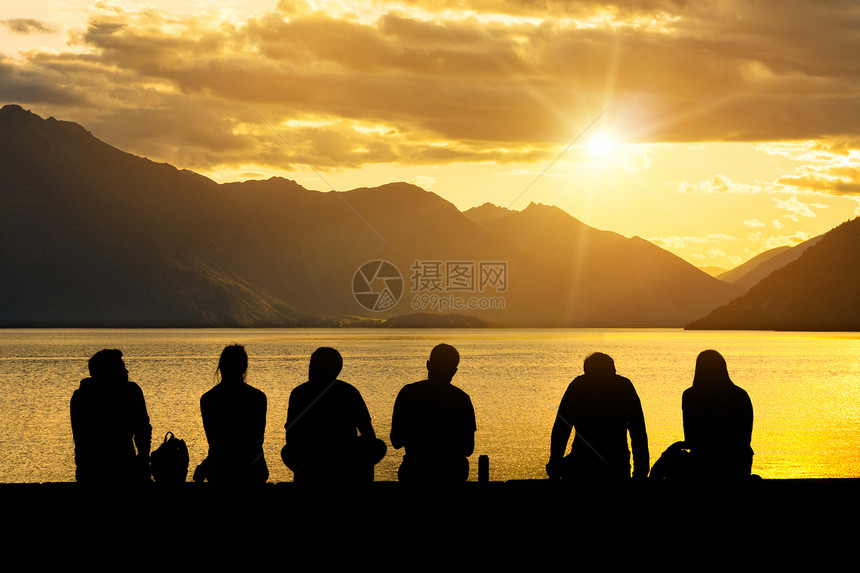 坐在湖边海滩看日落的青年们图片