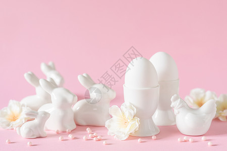 粉红色背景的白色鸡蛋和兔子装饰品图片