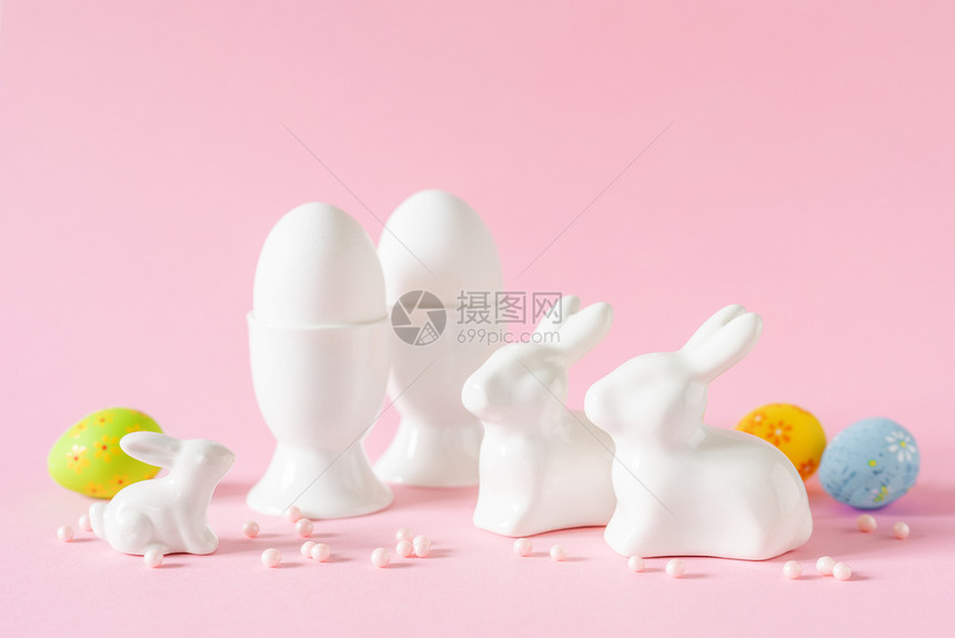 粉红色背景的白色鸡蛋和兔子装饰品假日装饰图片