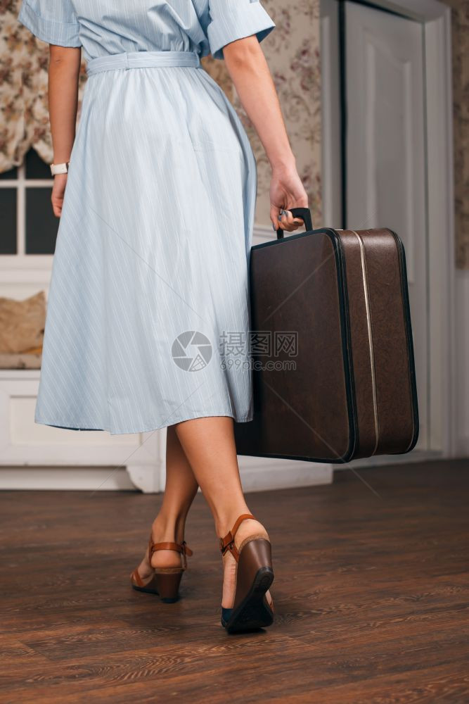 年轻女拿着手提箱准备外出图片